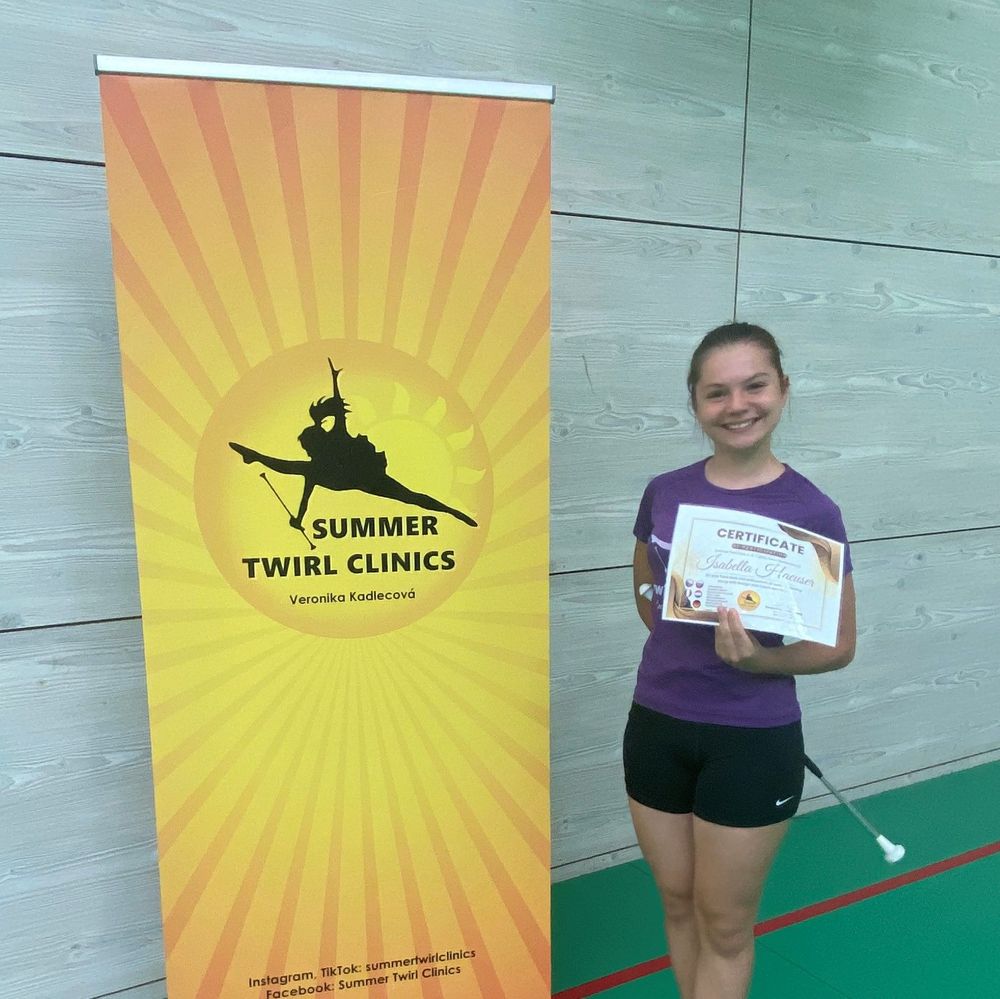 Twirlerin mit Urkunde vor Summer Twirl Clinics Banner