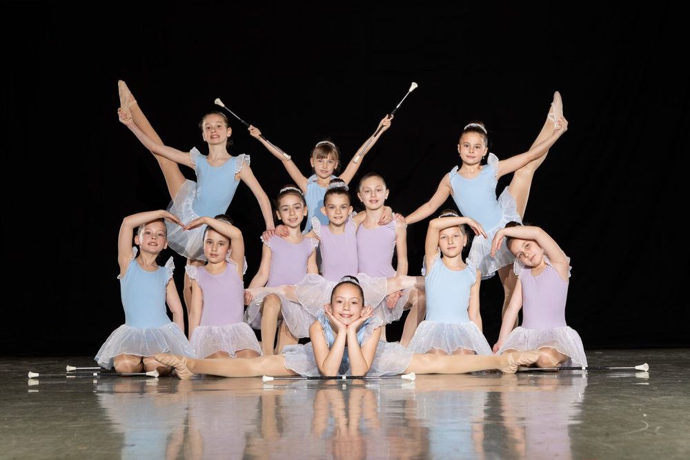 Kindergruppe in Ballettpose mit Twirling-Stäben