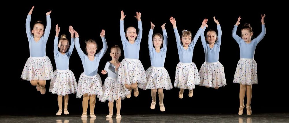 Springende Bambini-Tänzerinnen in blauen Trikots