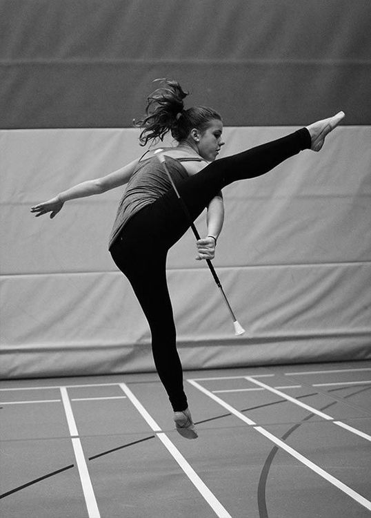 Twirlerin springt mit gestrecktem Bein und Stab
