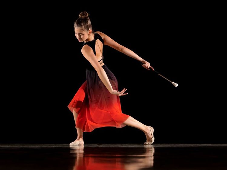 Twirlerin in rot-schwarzem Kleid mit Stab