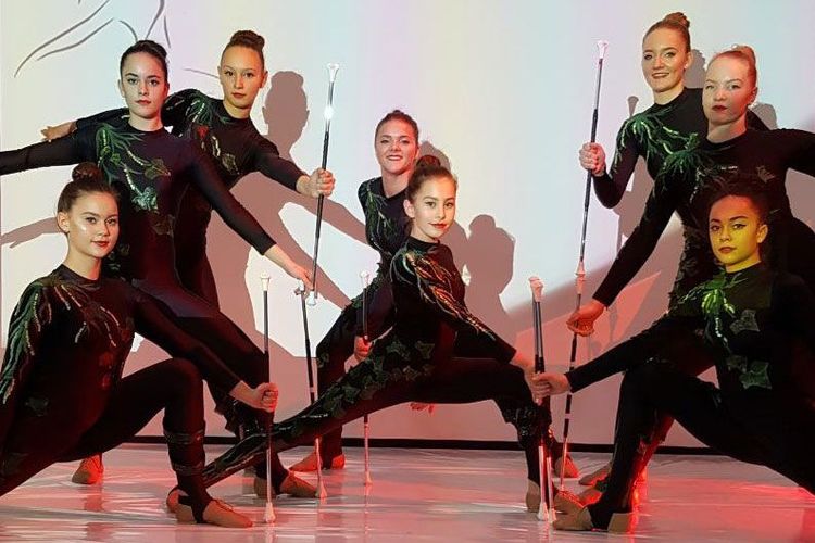 Team in schwarzen Kostümen mit beleuchteten Stäben